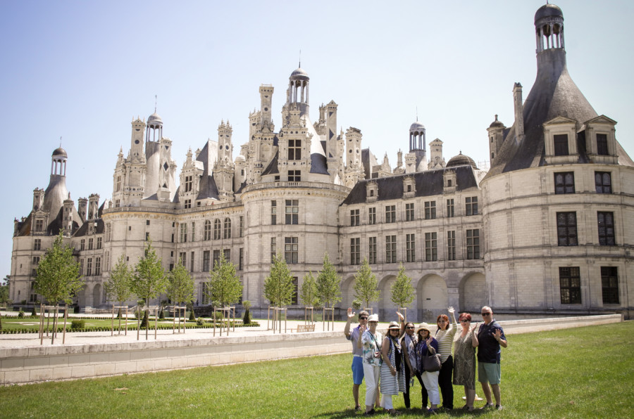 People posing and waving in front of a breathtaking castle, Loire Valley Tour Itinerary