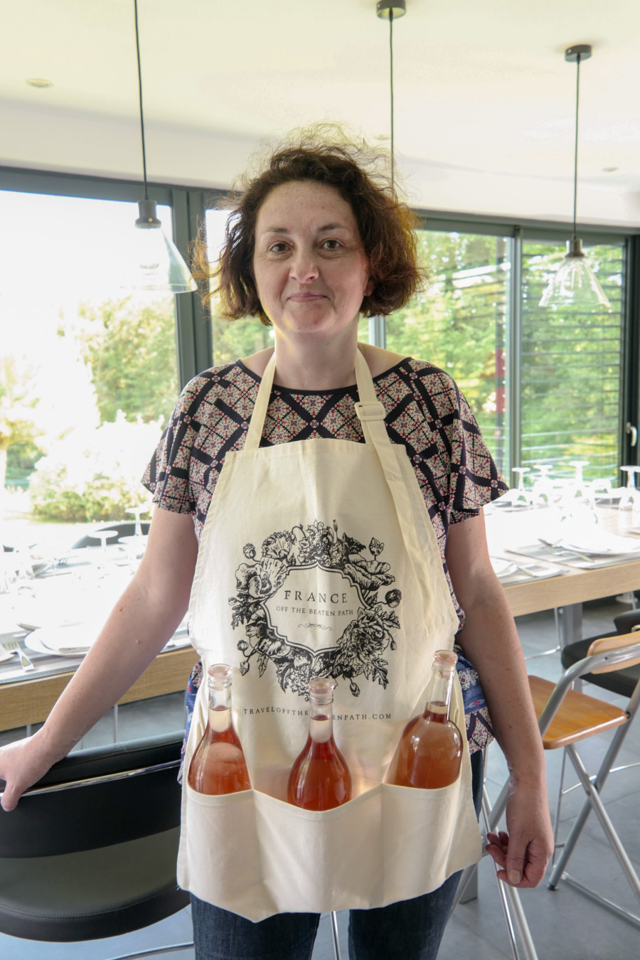 Woman on a cooking class, in an apron, with three bottles of rose wine placed in the apron