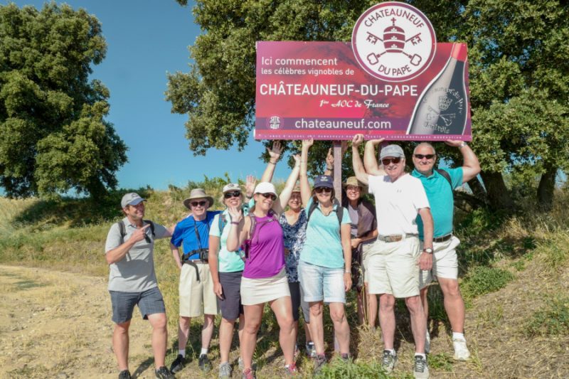 happy tour guests walking through vineyards in Provence