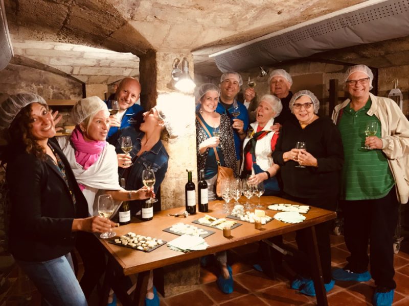 People wine and cheese tasting in rustic basement of an old castle within Bordeaux Tour. Check out 2024 Bordeaux Tour dates