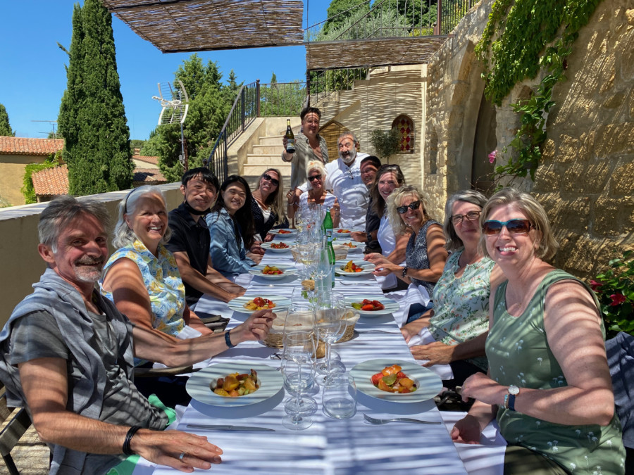 Group of happy people enjoying the lunch on a rustic terrasse within the Provence Walking tour