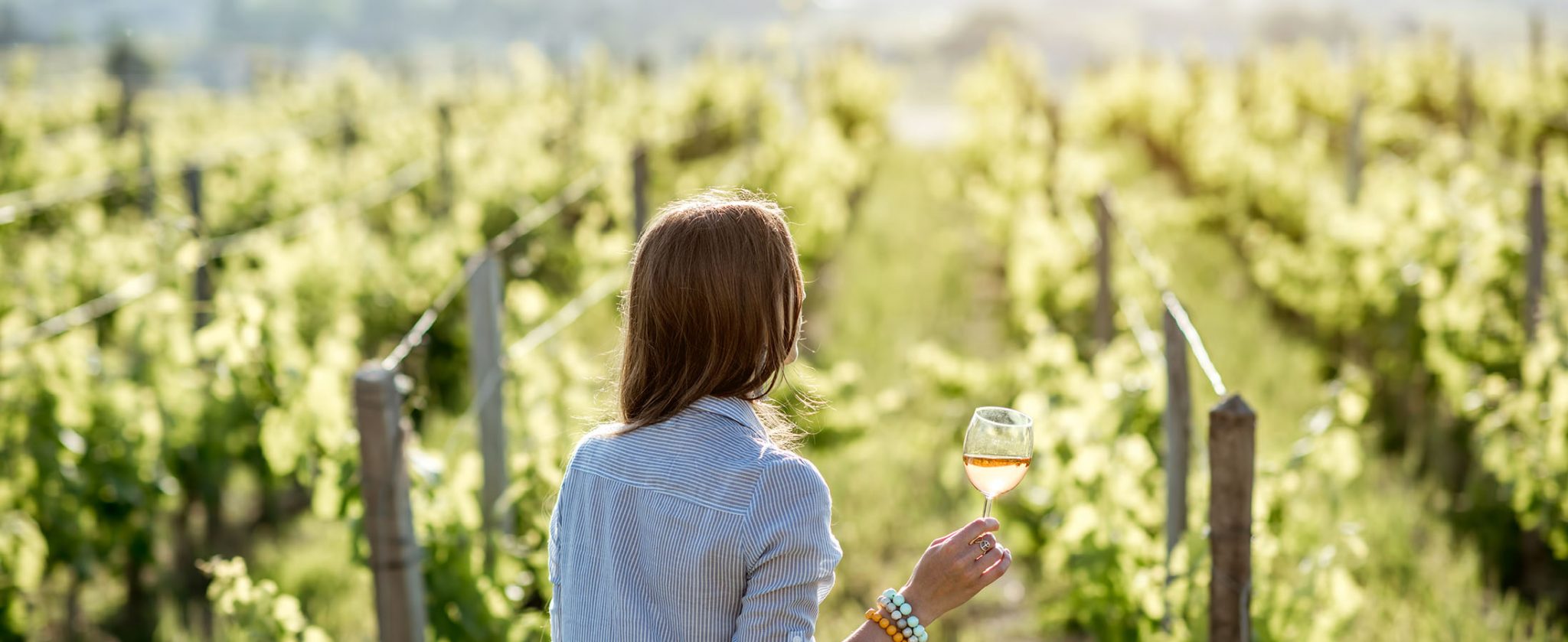 Woman in the grape fields holding wine glass, and enjoing her FRANCE OFF THE BEATEN PATH™ tour