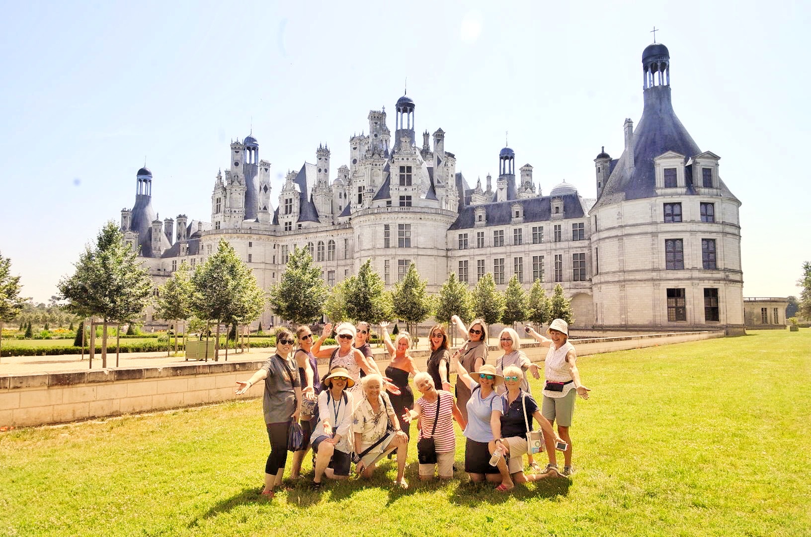 Happy group of people poing in front of the beautiful old castle - Lorie Valley tour. Check 2024 Loire Valley Tour dates