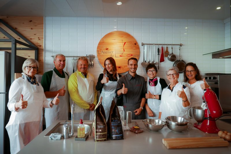 People on a cooking class, in aprons, posing with thumbs up enjoying champagne tour itinerary 