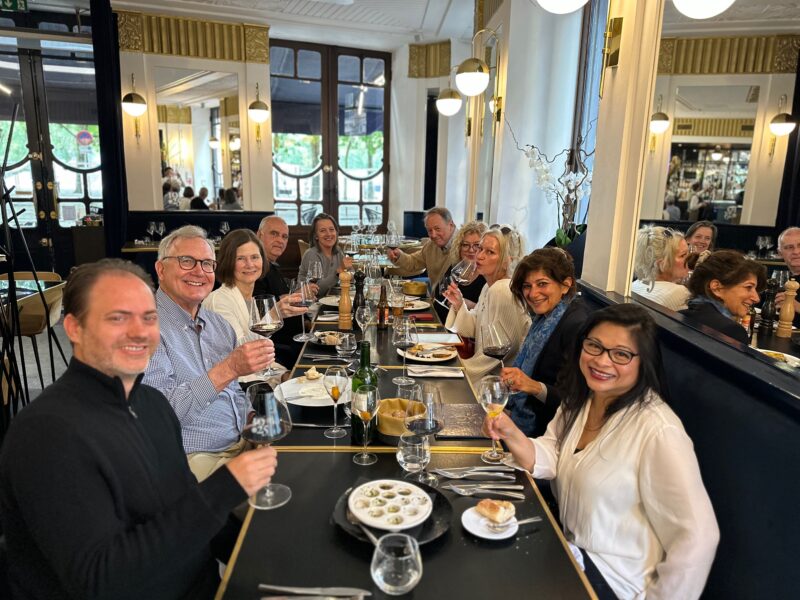 A group of happy people are toasting with raised glasses. Check our Bordeaux Tour Itinerary